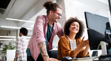 Photo of two smiling corporate employees in front of a computer