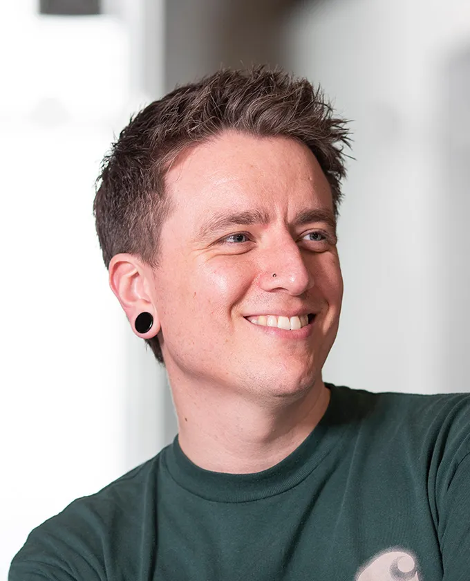 a headshot of Christian, he is wearing a green jumper and smiling at something off camera