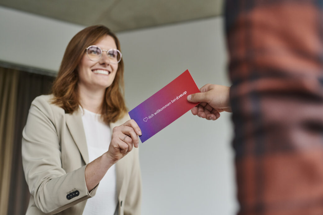 Mitarbeiterin überreicht einem Kollegen einen Umschlag