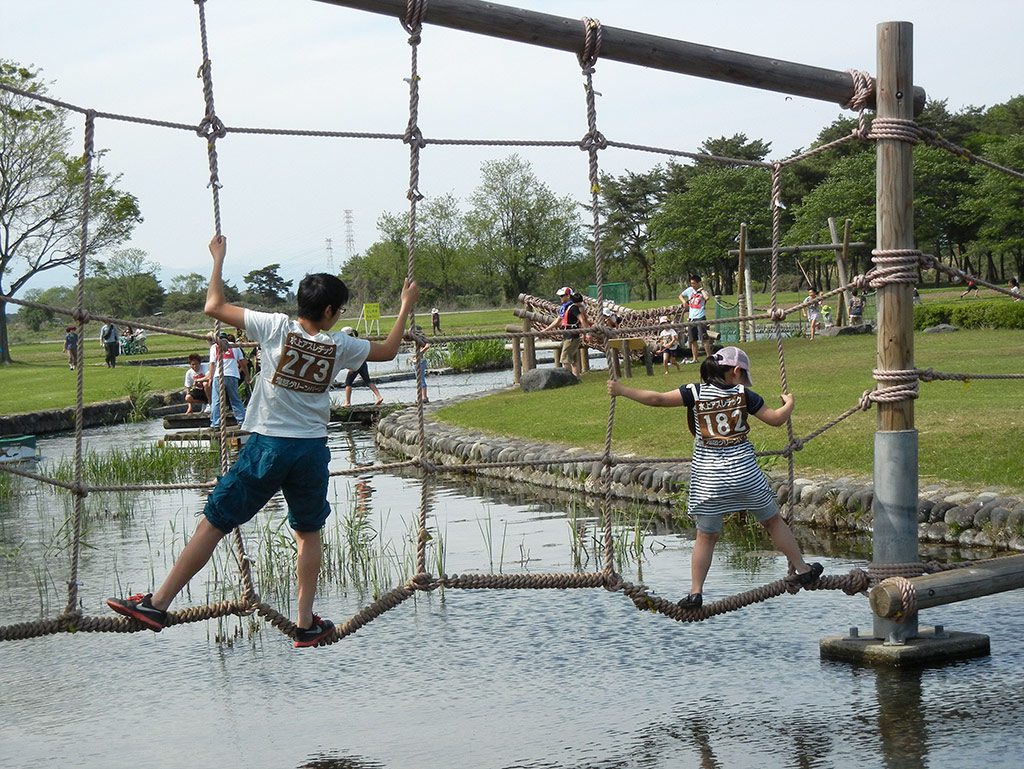 水上のネットを進む子どもたち/鬼怒グリーンパーク水上アスレチック(栃木県/高根沢町)