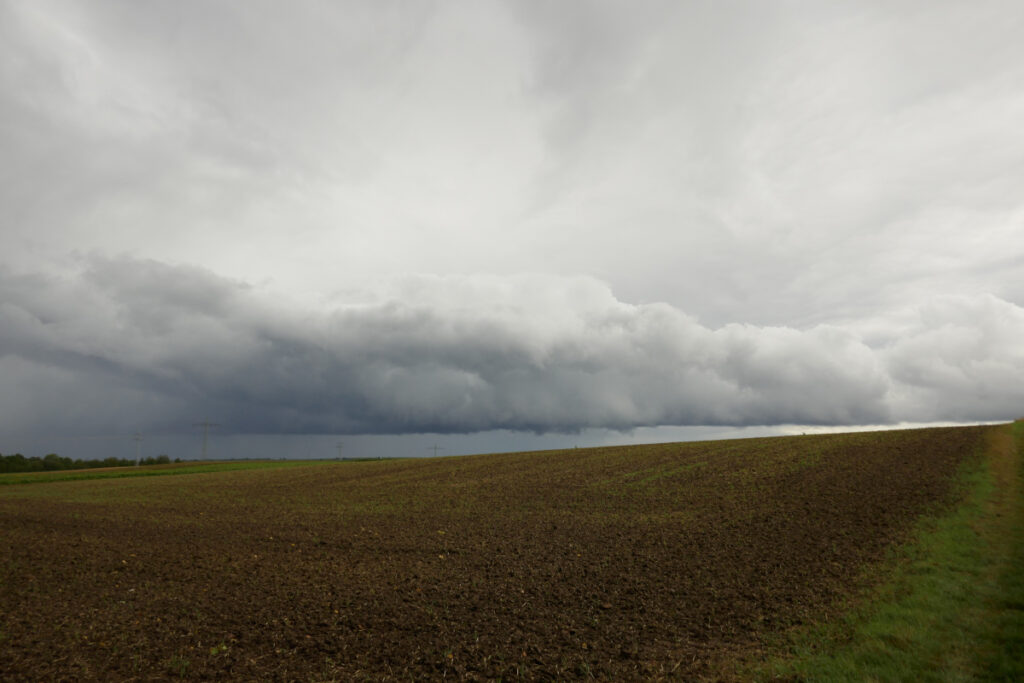 Wolkenwand und Regen über Acker