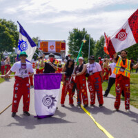 Group of first-year students posing for the camera holding flags with the McMaster engineering logo.