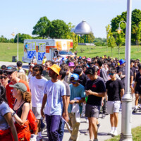 A large group of first-year students and representatives walking in front of a U-Haul reading ' HSR BUS'.