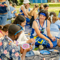 Faculty representatives and first-year students painting on tarps.