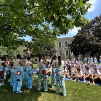 First-year students sitting on a tarp listening to faculty representatives.