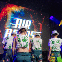 Representatives on a stage with their backs facing the camera in front of a stage projector that says 'AIRBANDS'.