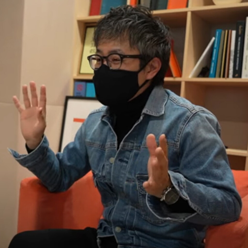 PLOTTER director Takayuki holding up both hands to explain the PLOTTER system.