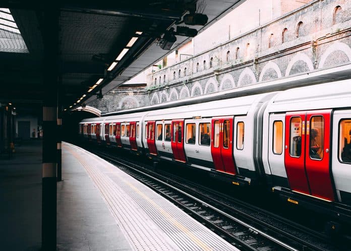 Red and White Train at a Station A red and white train is stationed on a platform with an arched ceiling and empty tracks.