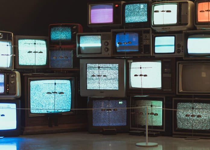 Vintage TV Stacks Photo of multiple vintage televisions stacked on top of each other, showing static on their screens.