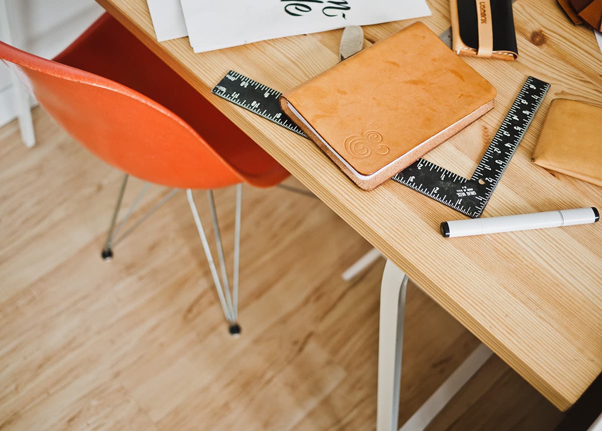 Orange Chair and Desk with Office Supplies Photo of an orange chair and a desk with office supplies like rulers and a notebook.