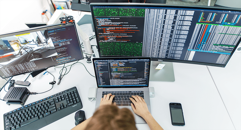 woman working across multiple computer screens and monitors