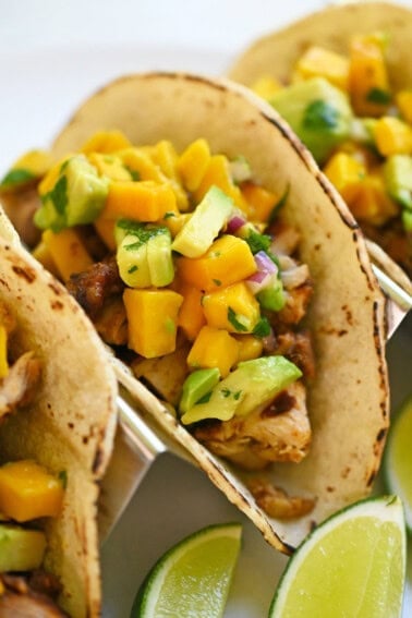 A closeup shot of homemade chicken tacos topped with mango salsa.