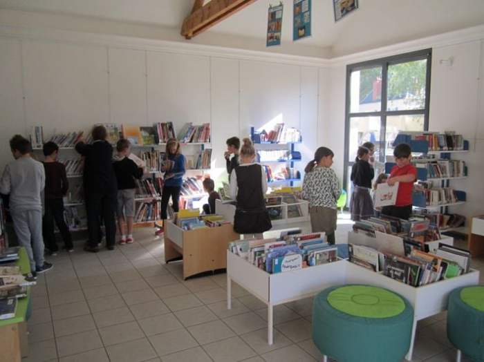 Several children looking at bookshelves.