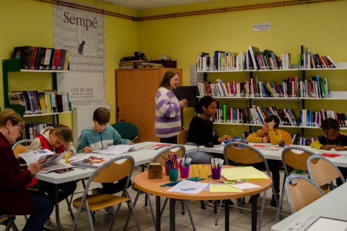 Several children sitting at desks doing creative activities.