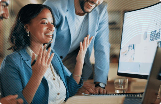 Young woman smiling and taking with colleagues in front of desktop computer