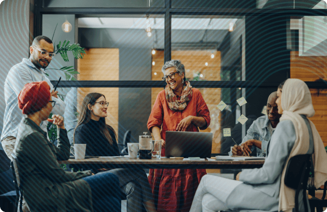 Group of coworkers smiling and talking around conference table in modern office