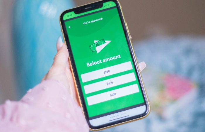 Dave cash advance Woman's hand holding phone that displays options for Dave cash advances