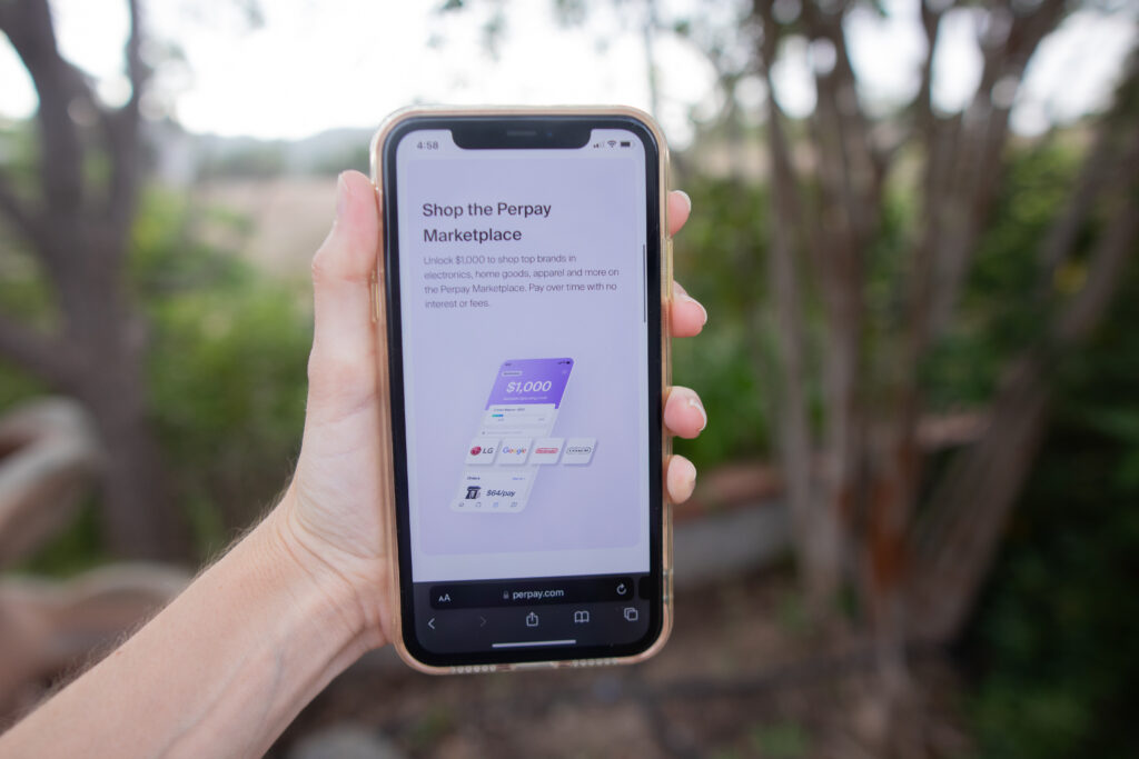 Woman's hand holding a phone. She is shopping in the Perpay marketplace.