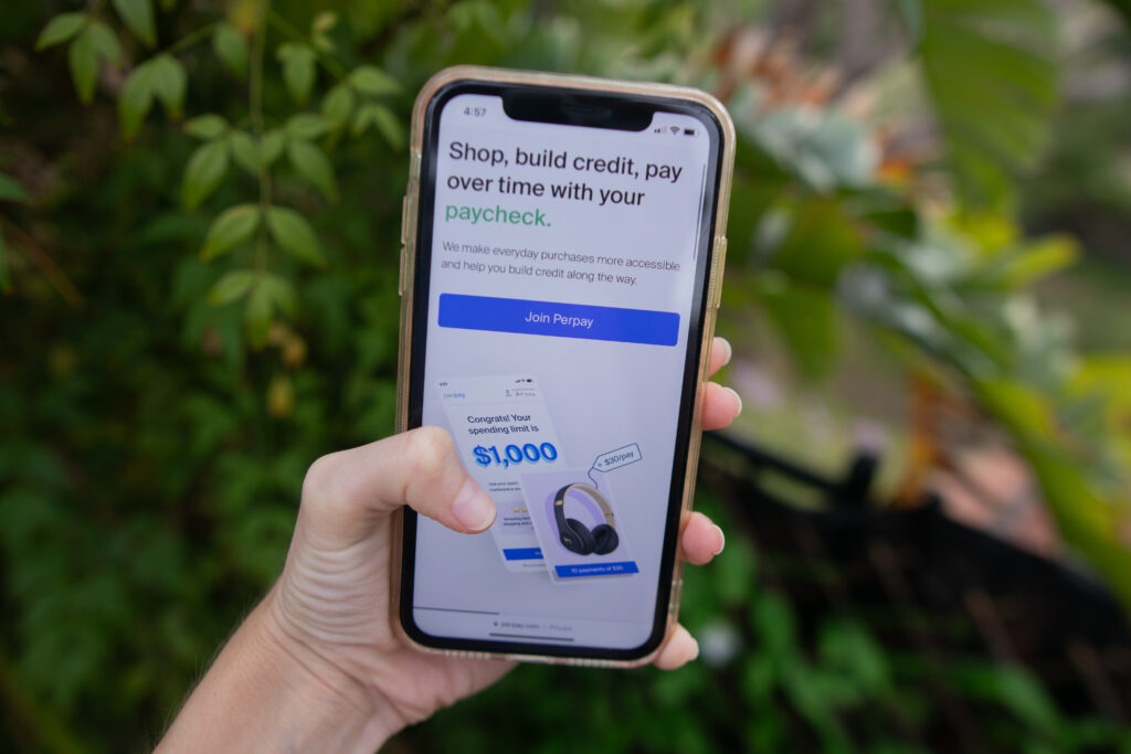 Woman's hand holding phone that displays the Perpay shopping app