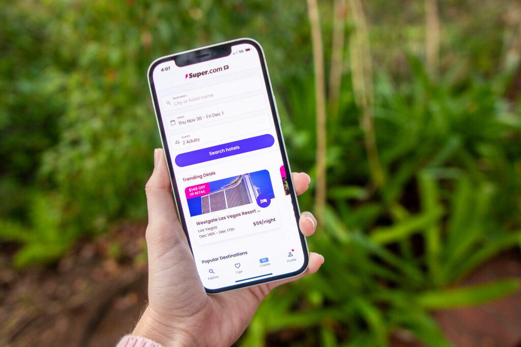 Woman's hand holding a phone that displays hotel bookings on super.com app