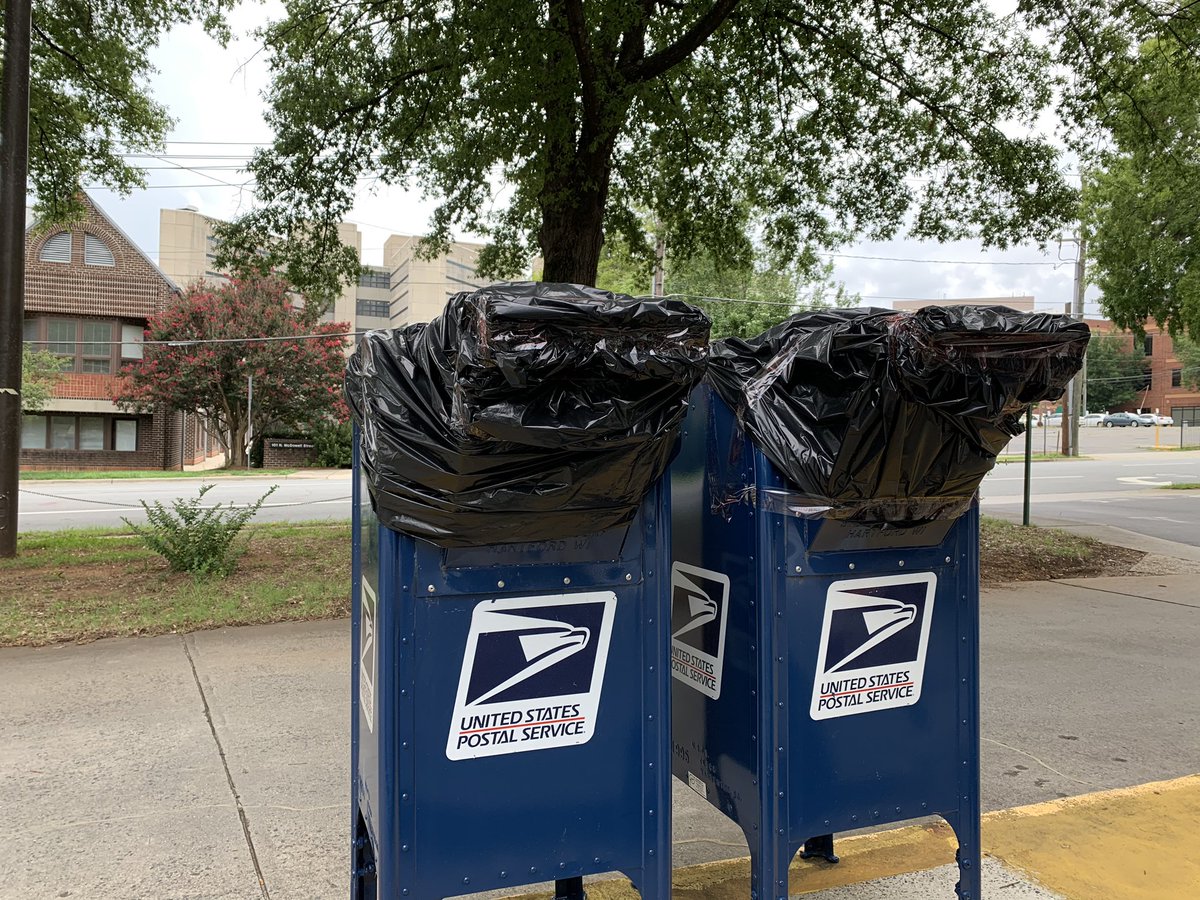 Two blue post office boxes with trash bags covering the mail slot
