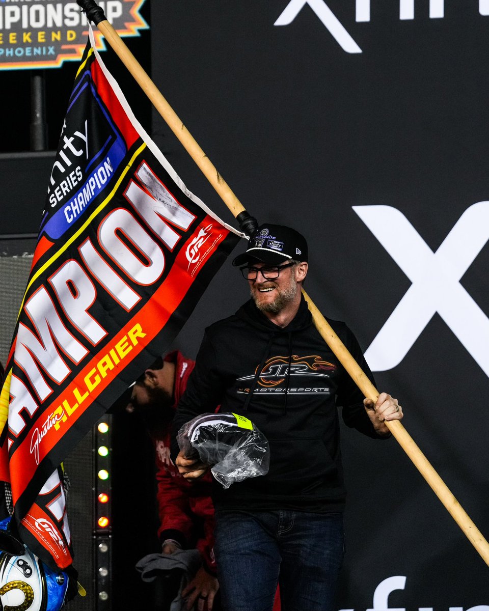 Dale Earnhardt Jr. smiles in Victory Lane while holding the championship flag.