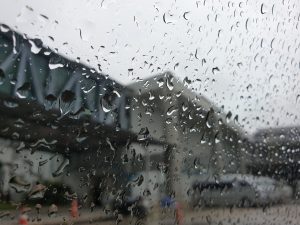 A view through a rain-speckled window, showing droplets of water collecting on the glass.