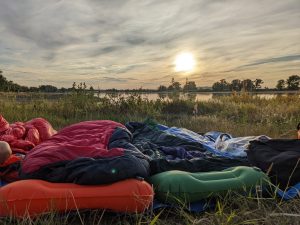 Sleeping setup in front of the sunset before a river on a bike tour.