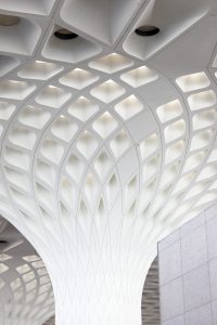 A modern white geometric ceiling of Mumbai airport, with a honeycomb-like pattern.