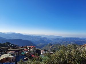 A village surrounded by mountains beneath the vast expanse of the sky within a natural setting.