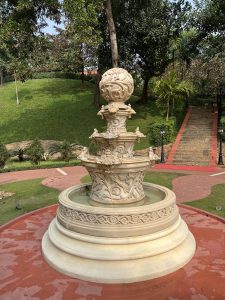 A serene park scene featuring a marble fountain, tree, creating a peaceful ambiance