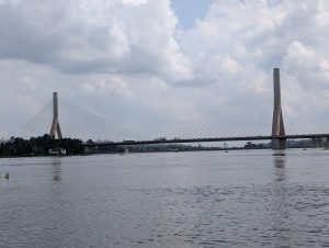 A view of a modern cable-stayed bridge spanning a wide Nile river, with tall concrete pillars and cables supporting the roadway