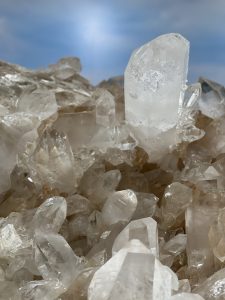 Large quartz crystal cluster with sharp, transparent points rising from the base, displayed against a sky-blue backdrop at the National Museum of Natural History