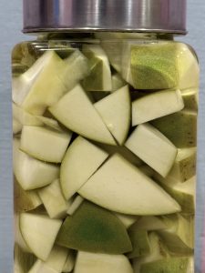 Cut raw mango pieces stored in a glass jar filled with liquid in Perumanna, Kozhikode, showing homemade preservation commonly used in Kerala kitchens.