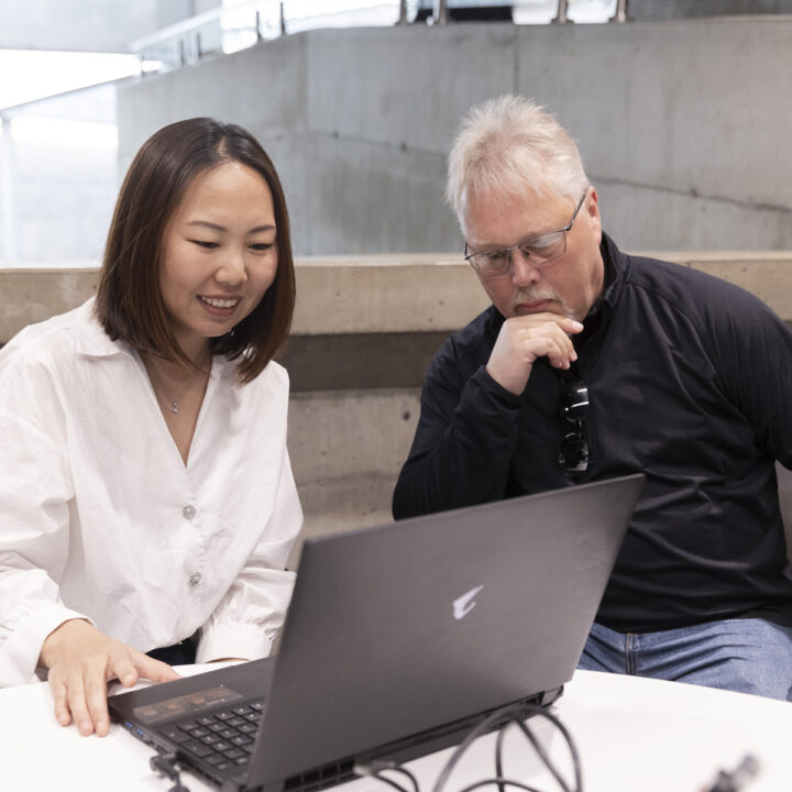 A man and a woman look at a laptop screen together