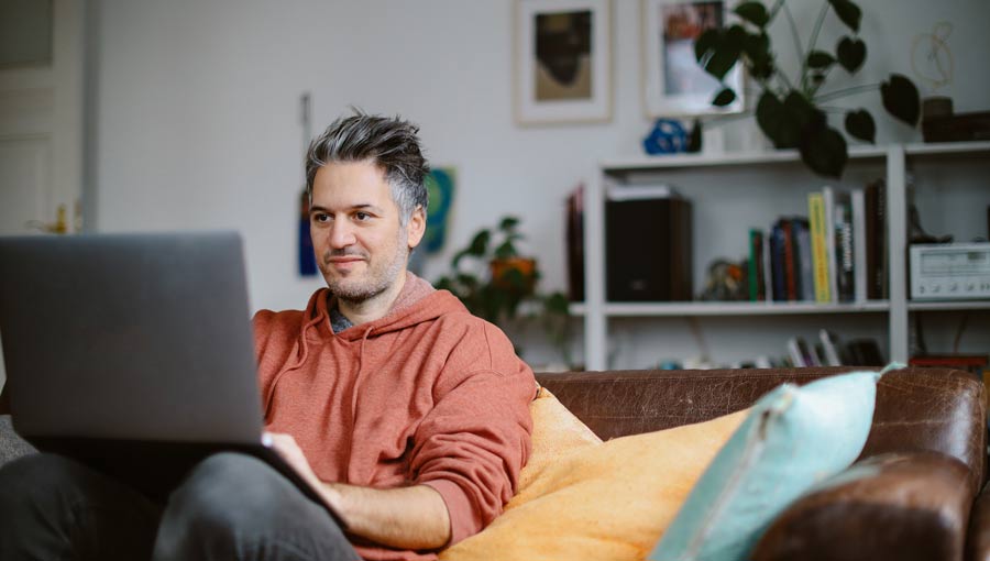 A person sits on a couch while learning how to write a value proposition on their computer.