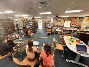 Students work on laptops while overlooking a course built for their Spheros.