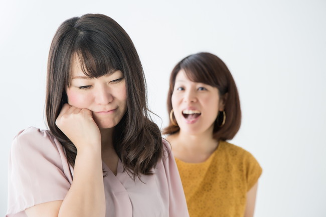 友人に話しかけられているが友人関係に悩んでいる様子の女性
