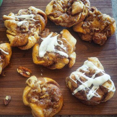 Praline crunch cinnamon knots on a brown cutting board.