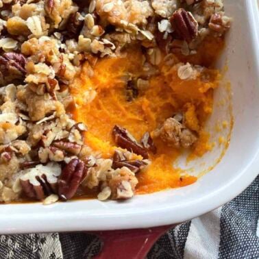 A pan of sweet potato casserole with a scoop missing.