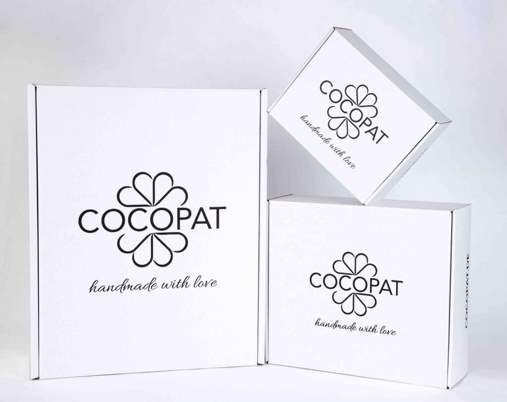 white cardboard Cocopat boxes with dark print on top