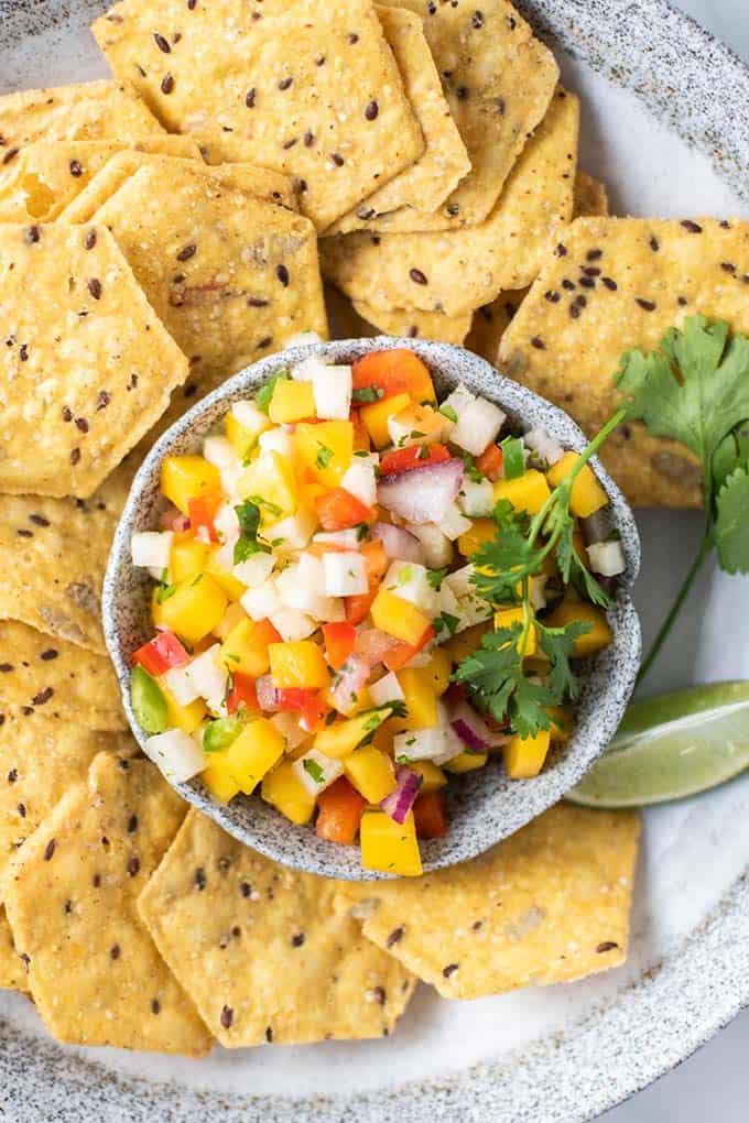 A bowl of multi grain chips with a dish of salsa in the middle.