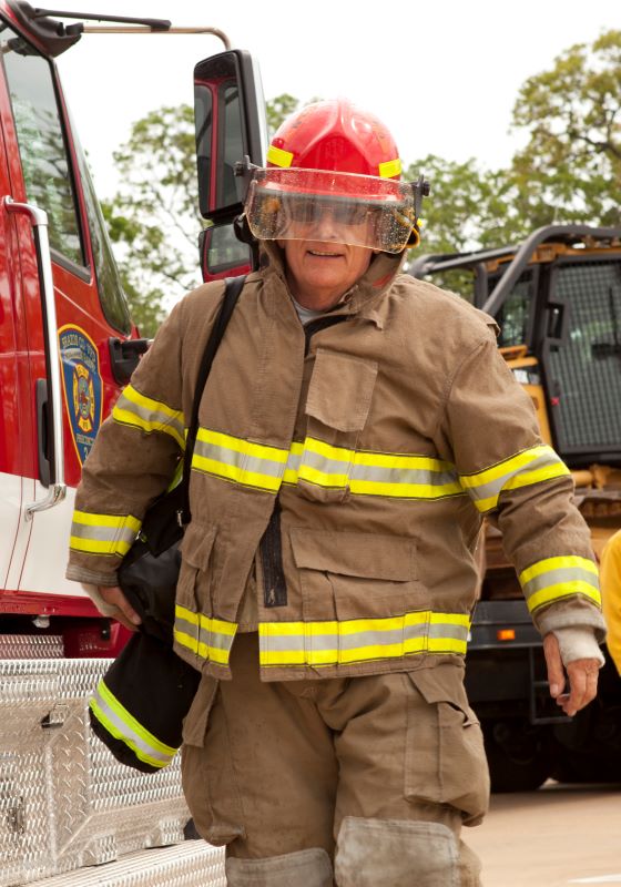 Firefighter with red hard hat on walking in front of fire truck