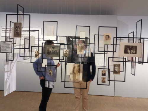 Ausstellungsansicht mit Rahmen und historischen Fotografien die im Raum hängen