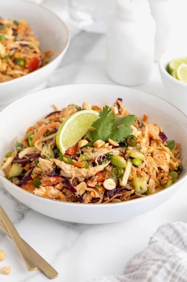 A white bowl filled with crispy rice chicken salad topped with a lime wedge.