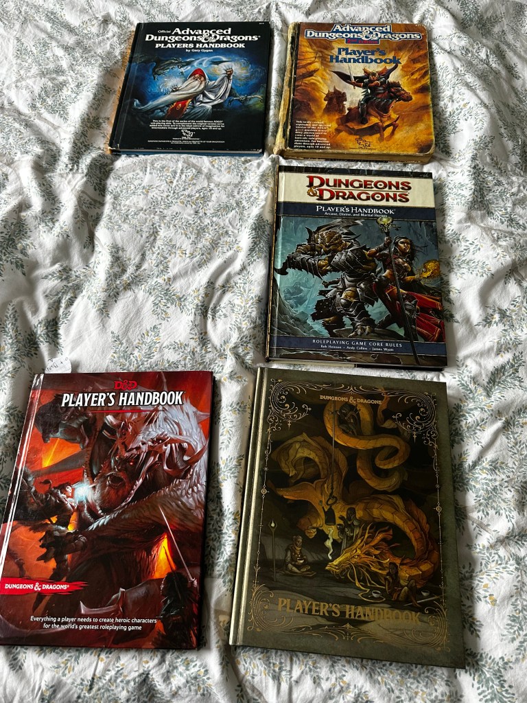 The covers of the Player's Handbooks for Ad&D 1st Ed, 2nd Ed, 4E, and 5E 2014 and 2024. I am missing a representative from either 3 or 3.5.
