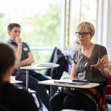 Photo of people sitting at desks in conversation.