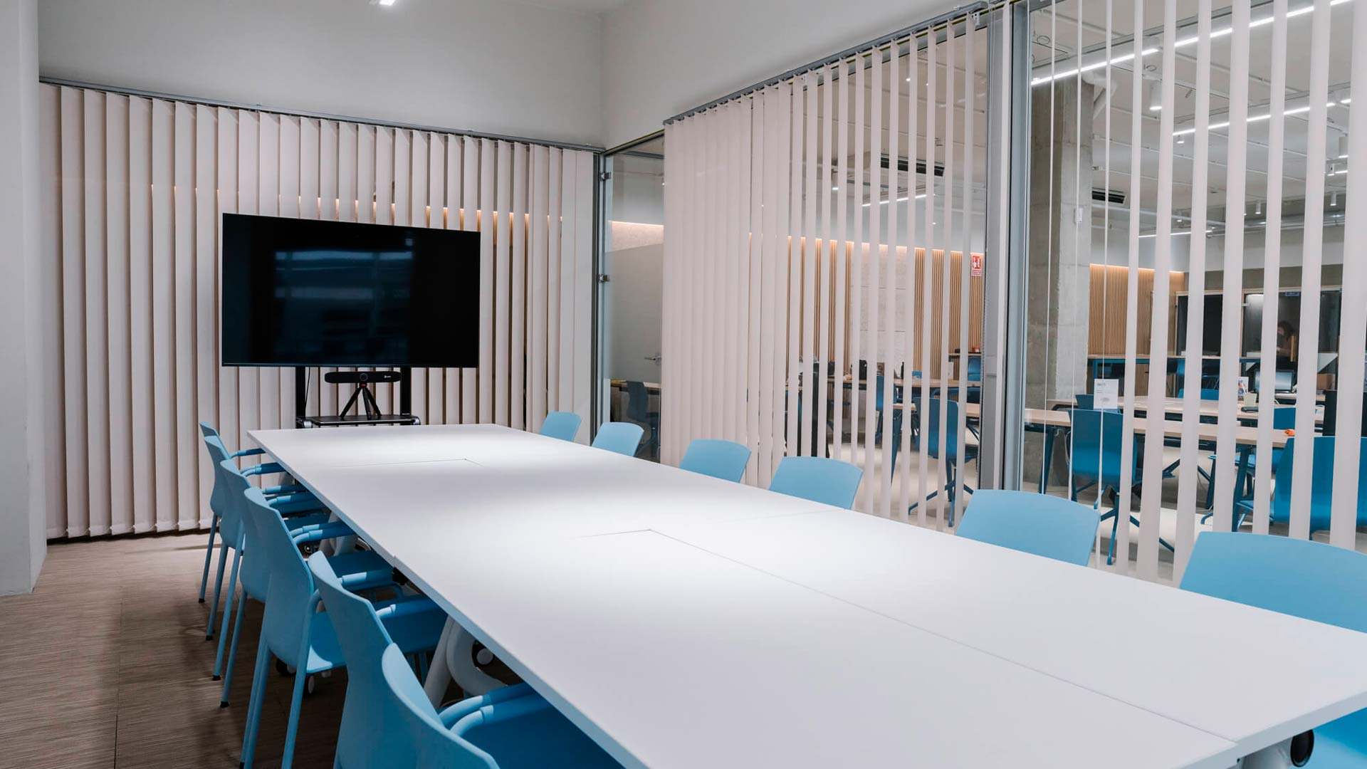 Mesa de reuniones blanca con sillas azules en oficina moderna.