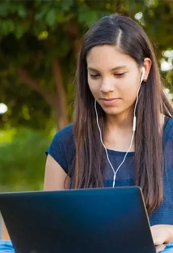 Young student doing online school in a park.