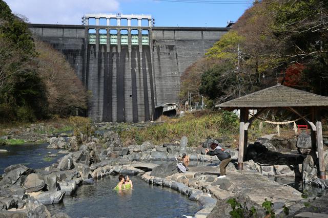 旭川の川底から噴き上がる天然の露天風呂「砂湯」。背後には湯原ダムがそびえ立つ=岡山県真庭市、上田潤撮影